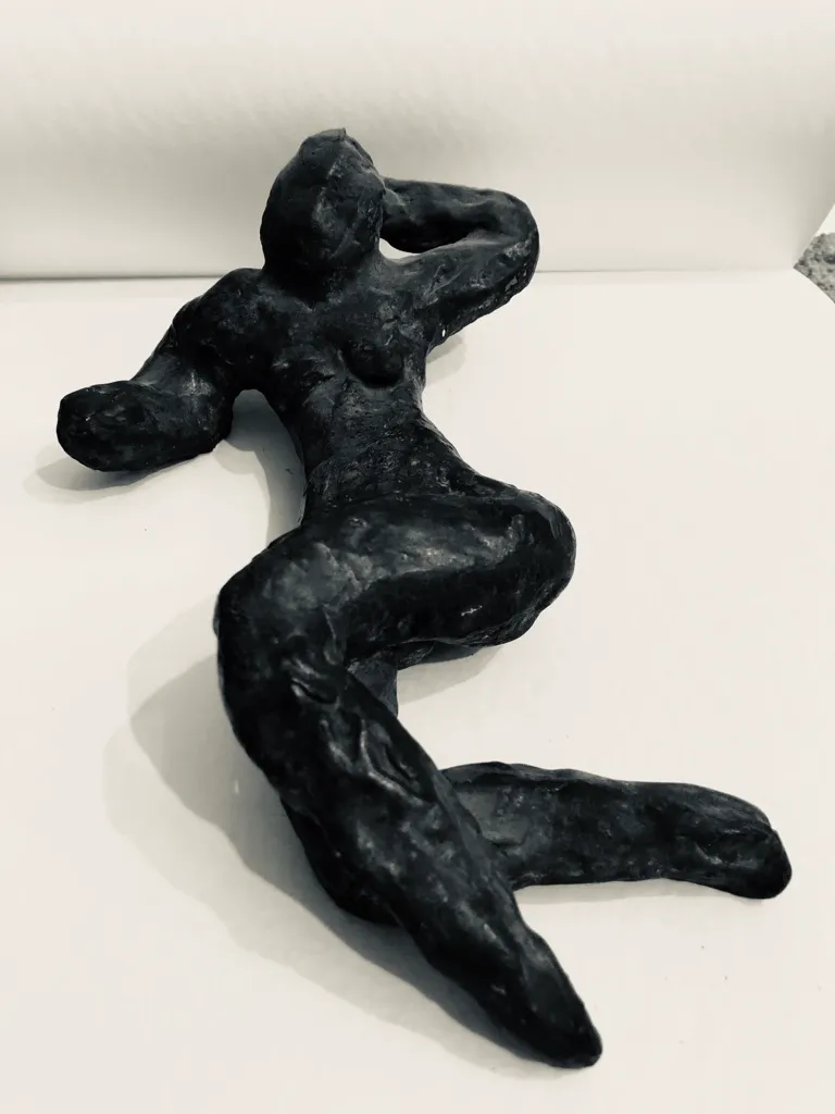 A black reclining figure seen from above, one arm bent behind the head.