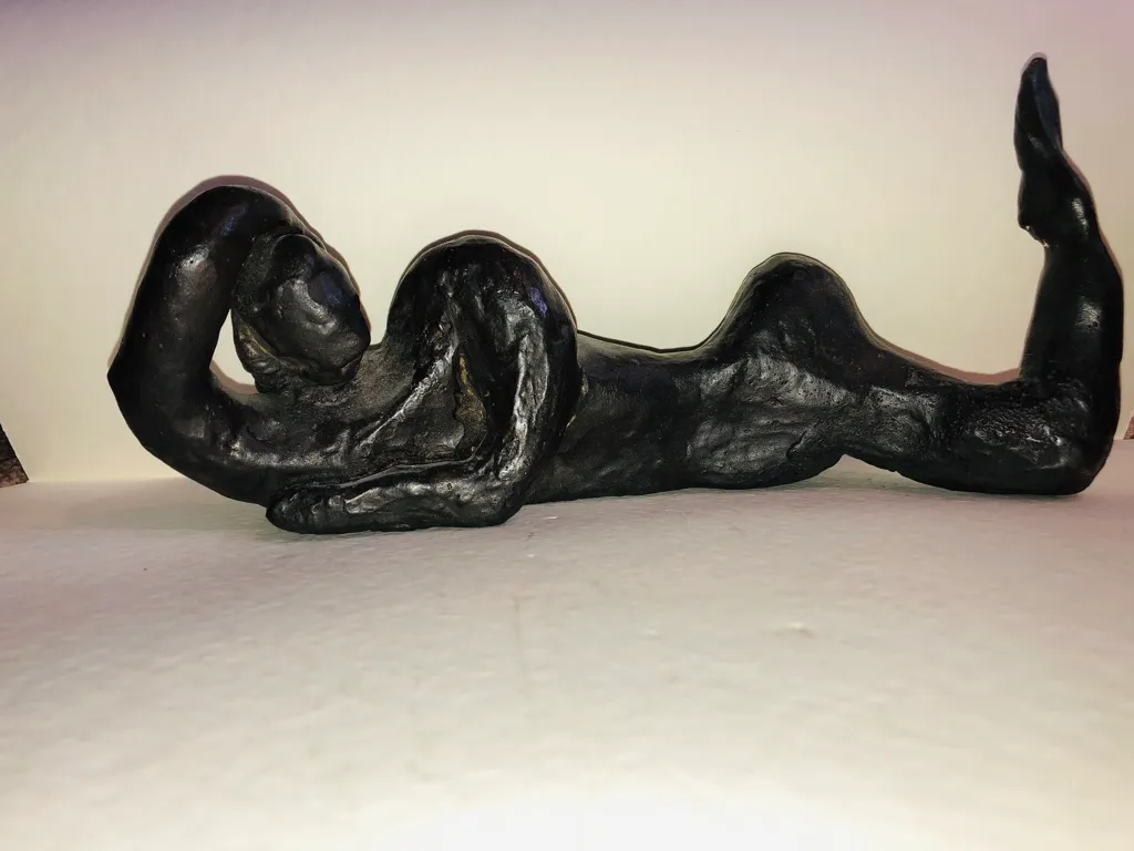 A black reclining figure photographed straight on, the raised leg at the right.