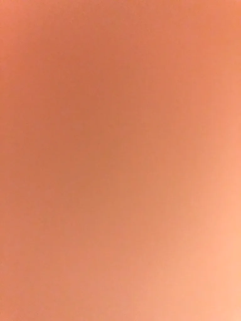 An out-of-focus photograph of a blank wall. No artwork is visible in this frame.