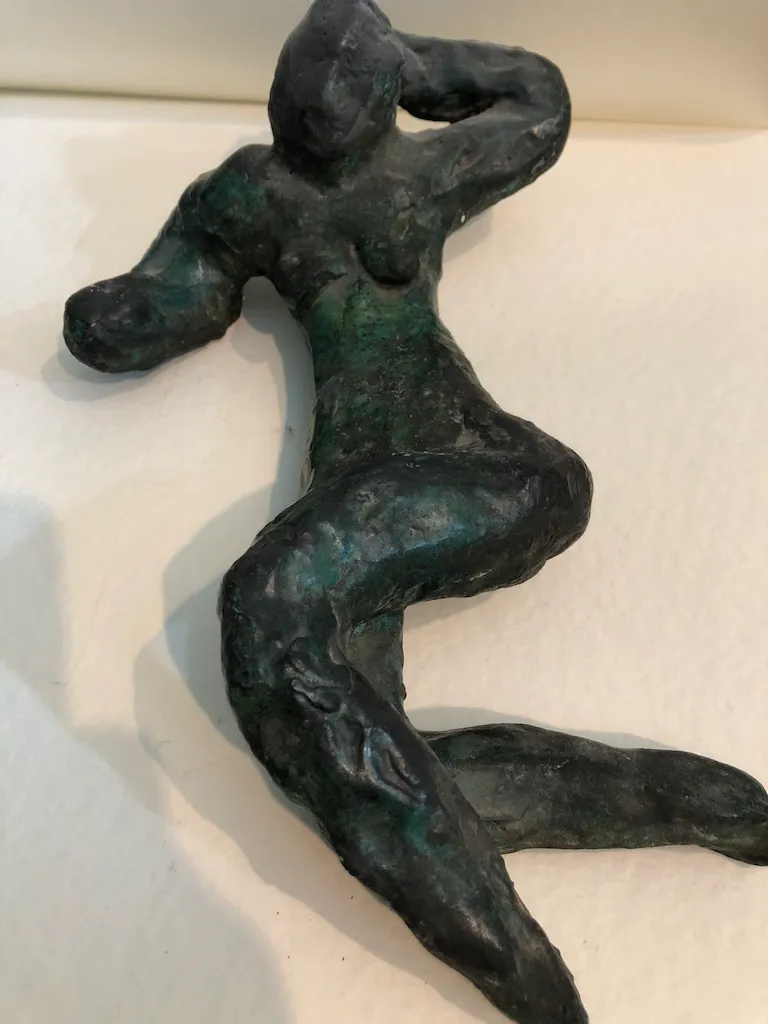The green-patinated reclining figure close up, her arm bent behind her head.