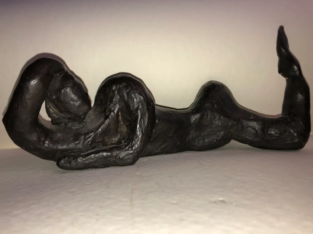 The black reclining figure in profile under a hard light.