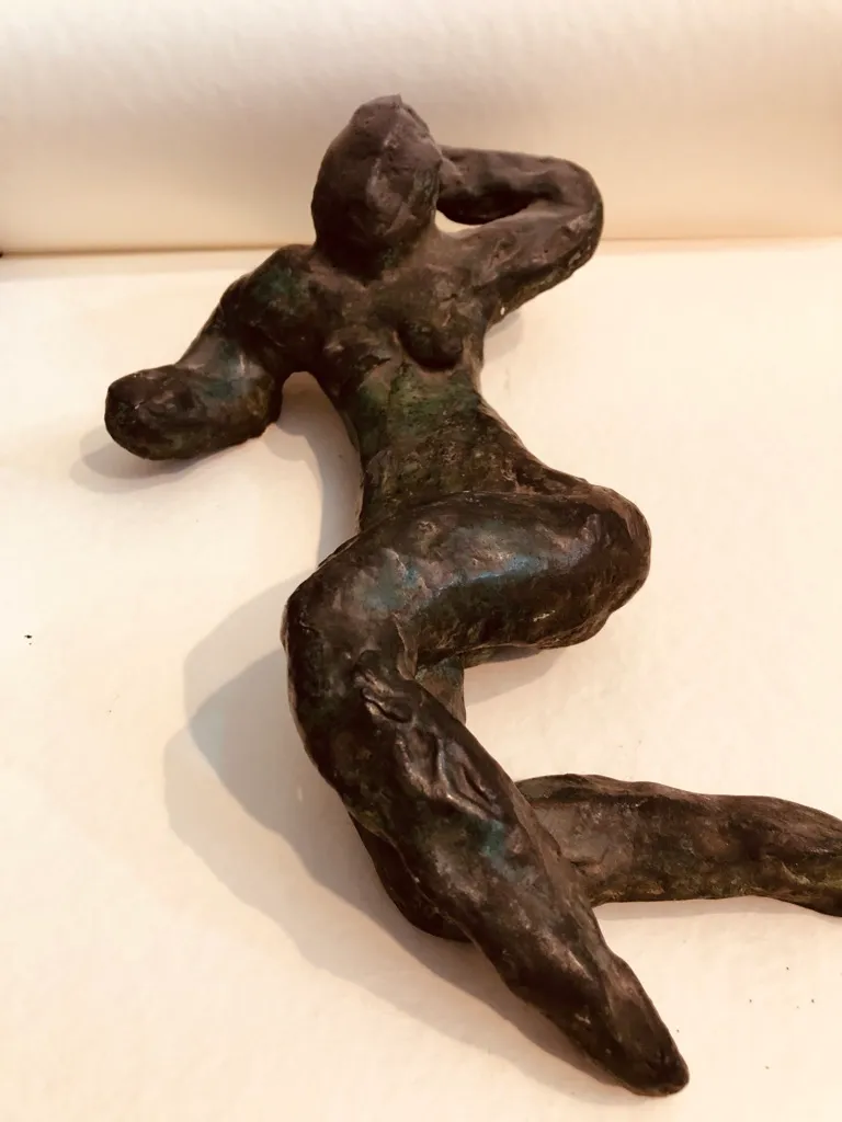 A dark green reclining figure, arm behind her head, seen from above.