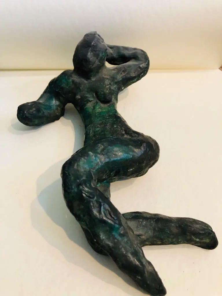 The green-patinated reclining figure, the patina brightest across her torso.