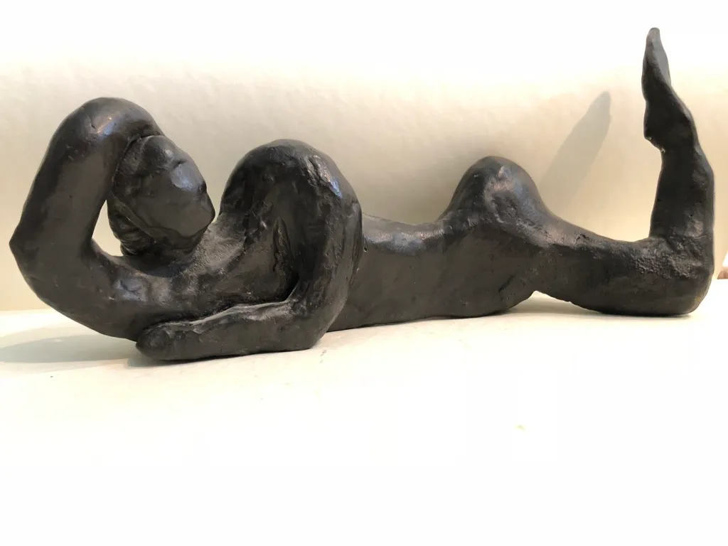 The black reclining figure, glossy, the raised leg at the right.