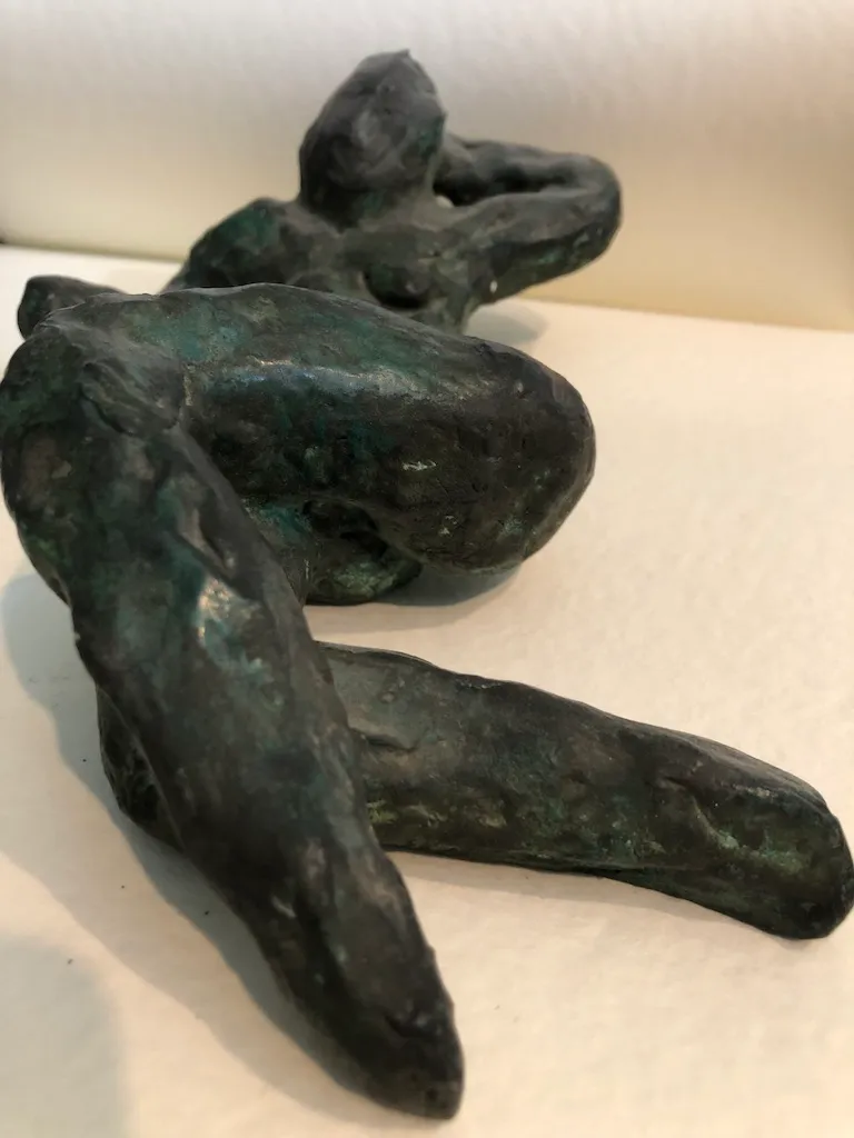 The green figure seen from beyond her legs, the torso and head receding into soft focus.